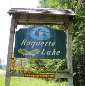 The sign that hangs by the roadside welcoming people to Raquette Lake