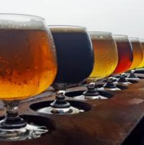 a row of short glasses filled with different types of beer