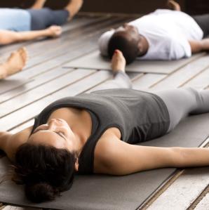Several people laying on their backs on yoga mats looking relaxed