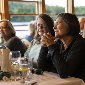 Three women sitting at a table on the WW Durant with glasses of wine in front of them having a good time.