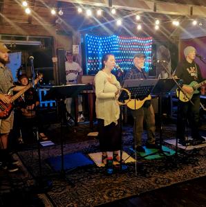 a band plays on an indoor stage in front of a light up American flag