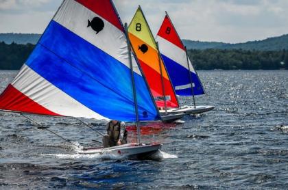 Three sail boats riding parallel to each other&#44; with one slightly ahead of the other.