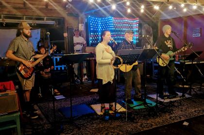 a band plays on an indoor stage in front of a light up American flag