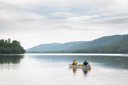 Two people in a canoe paddle across Lewey Lake.