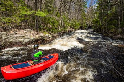 A whitewater kayaker heads towards some rapids.
