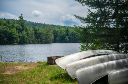 A few aluminum canoes next to the water.