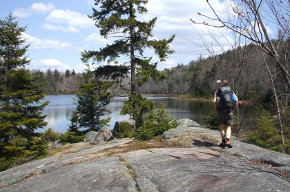 A woman walks towards a pond on an exposed granite trail.