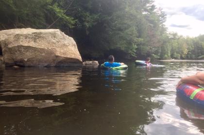  group of rafters floating by a big rock in the river