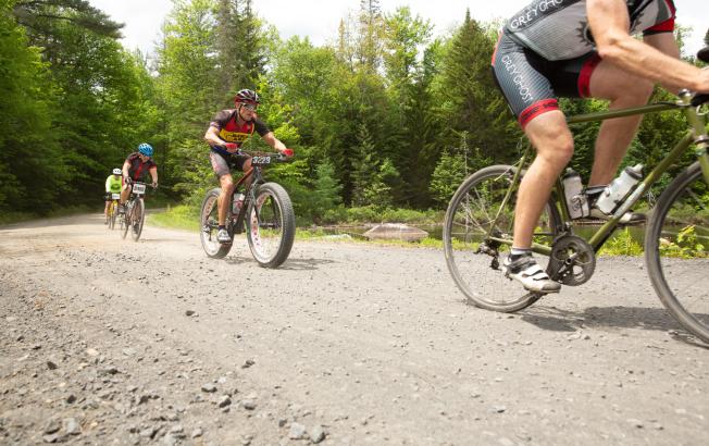 A group of cyclists ride on a gravel path.