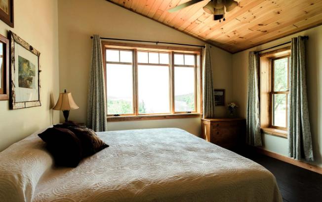 An inn guest rooom featuring large windows, rustic furnishings.