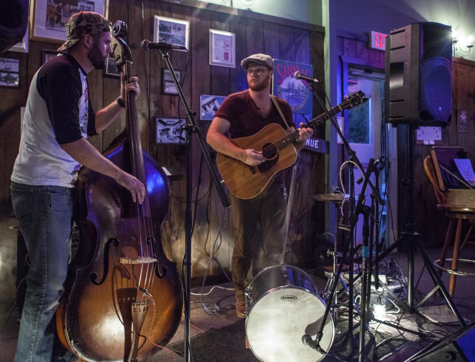 Two musicians play in a dimly-lit ski lodge bar.
