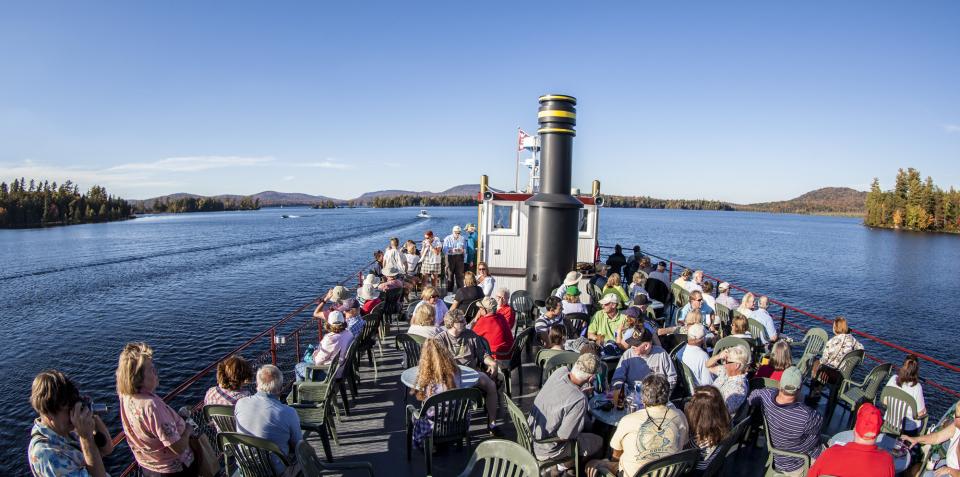 a crowd stands on the top deck of a boat.