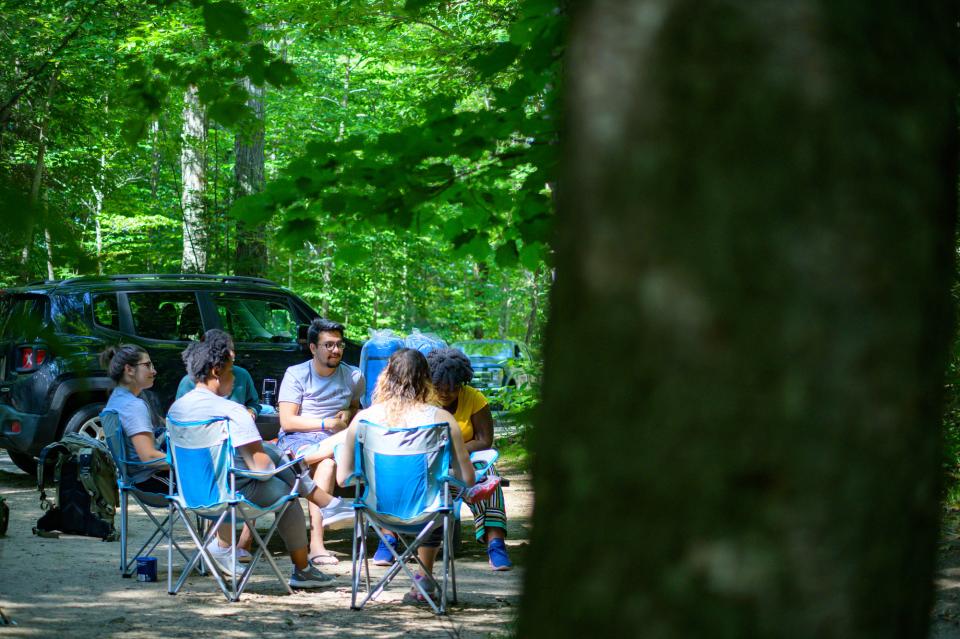 A group of campers chat in a circle of folding chairs.