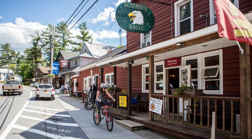 A cyclist rides past a restaurant downtown in a small Adirondack town.