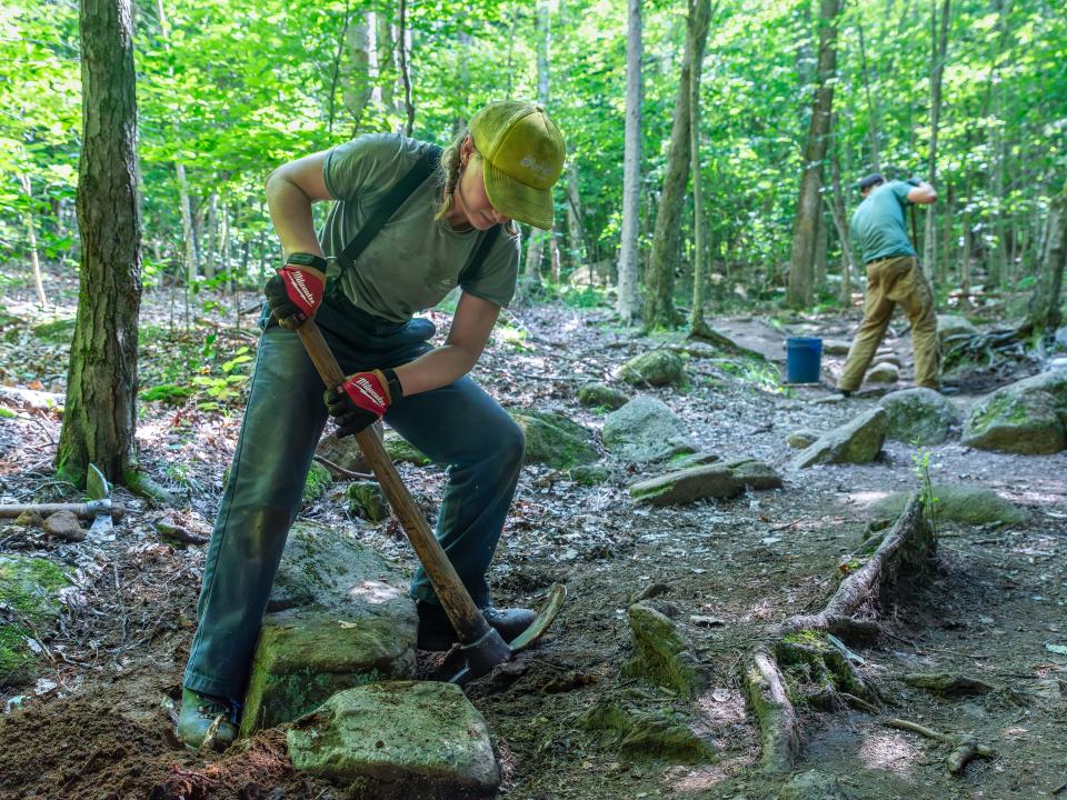 A trail crew member working on moving rock