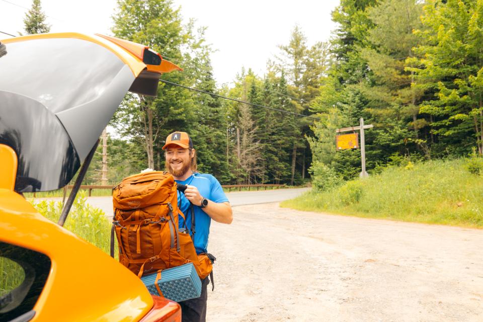 A hiker loads his backpack into a car