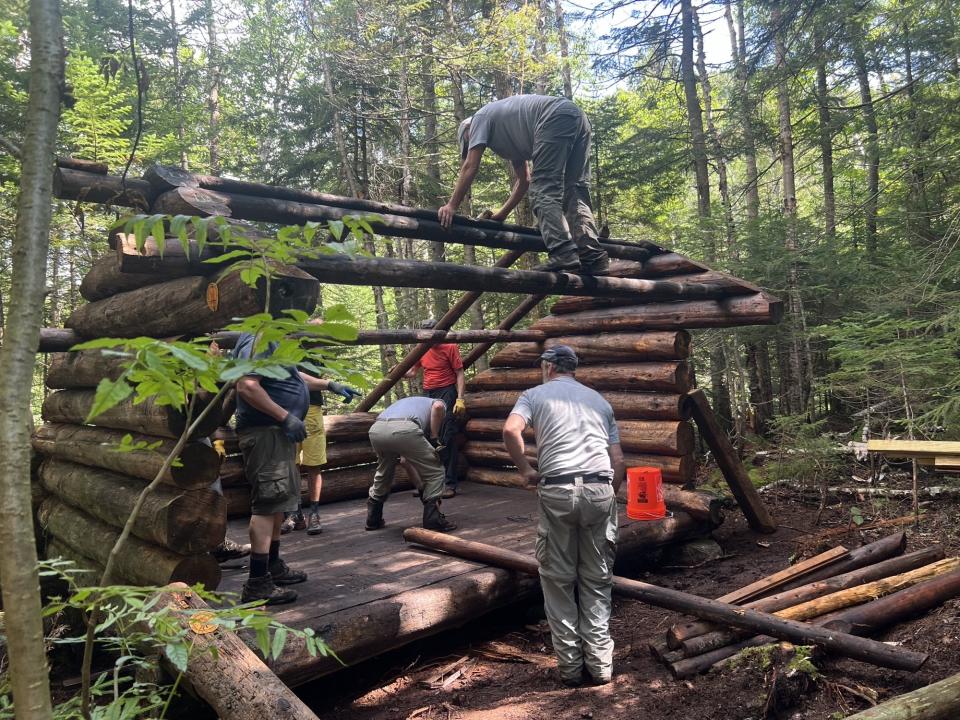 A group of people fixing up a wooden lean-to