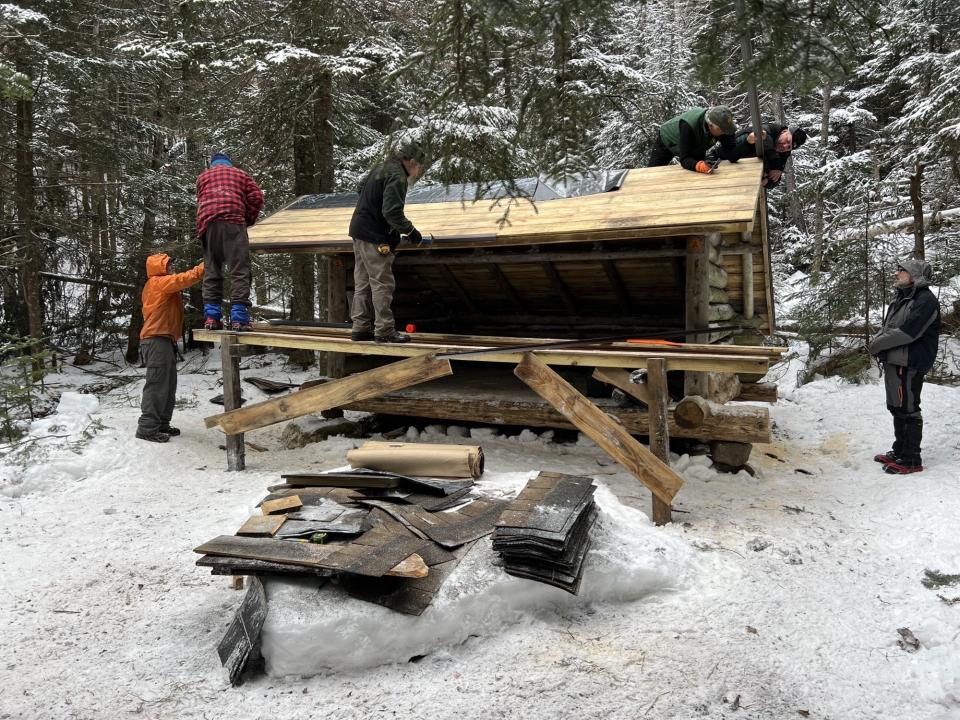 People working to fix a wooden lean-to in the winter