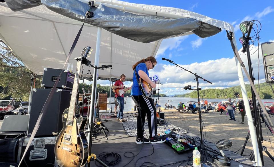 A band playing under a pop-up tent to a crowd at the Long Lake public beach