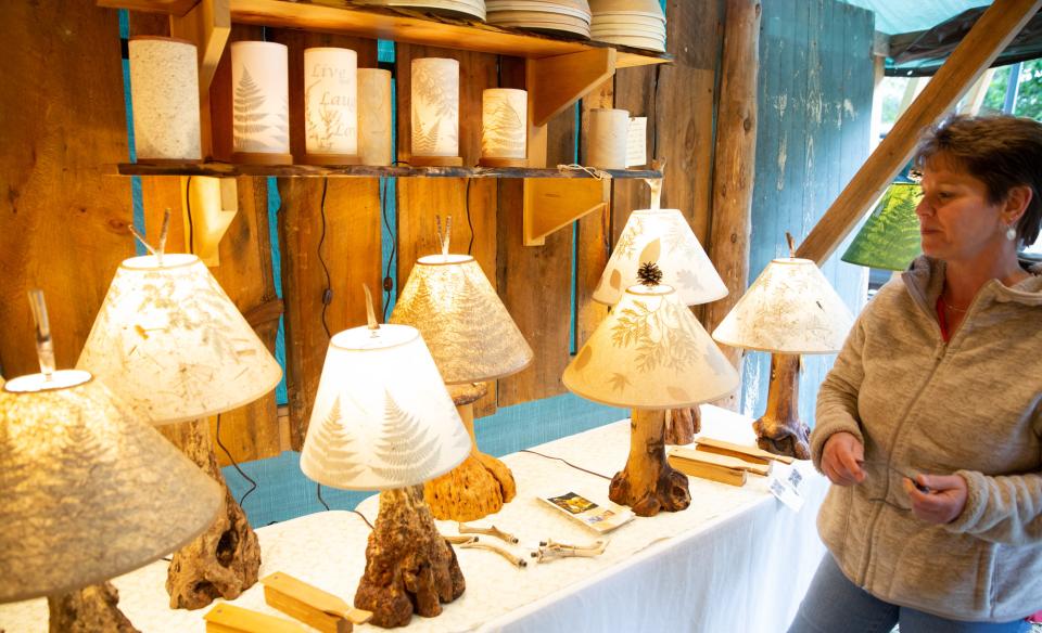 A variety of different lamps with hand made shades with fern and other rustic designs. The lamps bottoms are made of different wood or antlers