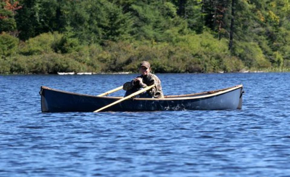person in canoe with binoculars in hand