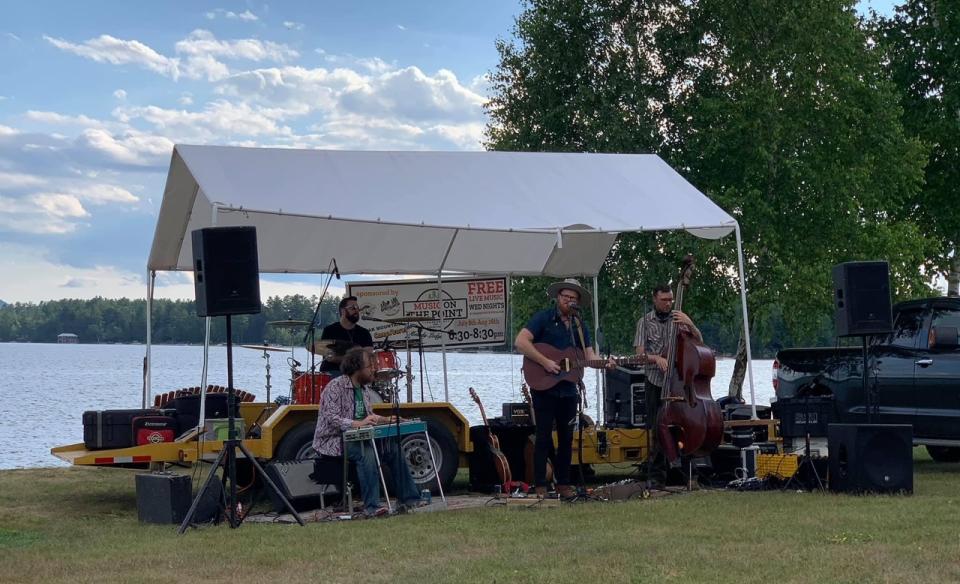 Music group playing under a canopy with Lake Pleasant in the background. blue sky with some white summer clouds