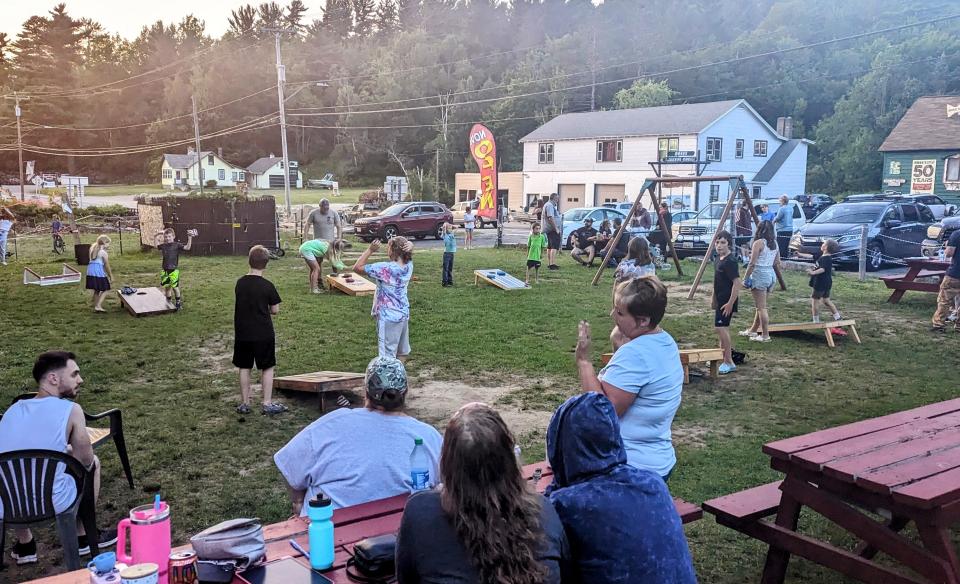 large group of people competing and watching a cornhole tournament