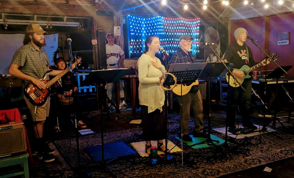 a band plays on an indoor stage in front of a light up American flag