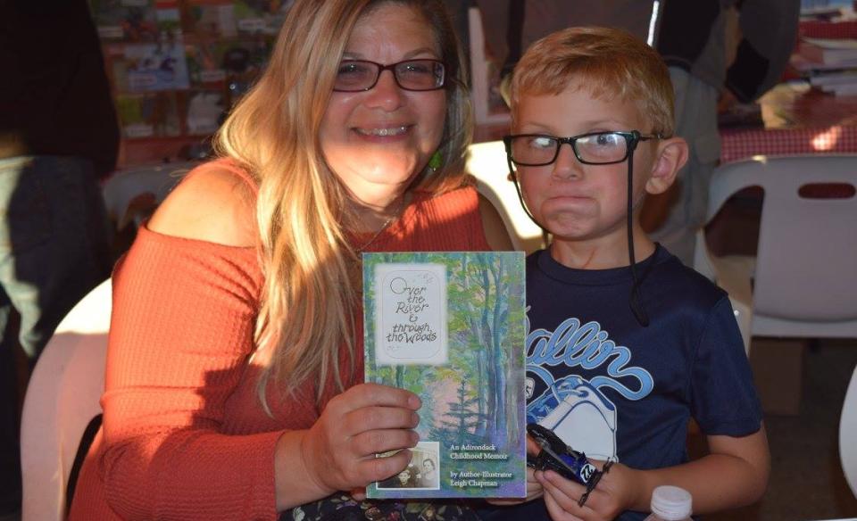 A child and adult pose with a book