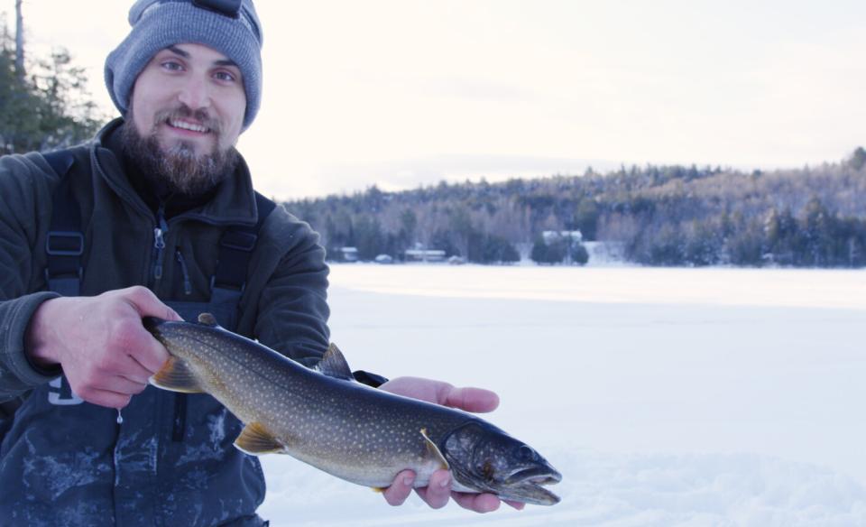 A man holding a fish he caught while ice fishing