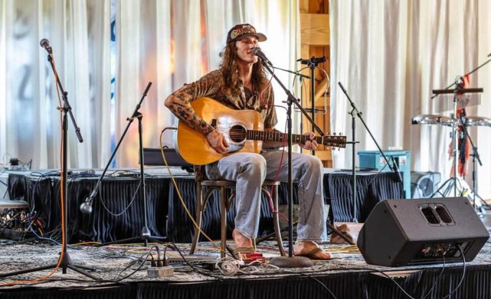 A photo of Carson Murphy playing his guitar on a stage