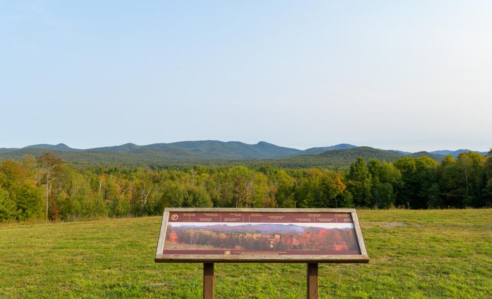 An interpretive sign at a roadside stop overlooking several mountains