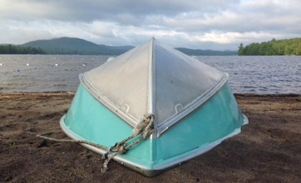 A large aluminum boat turned upside-down on the shore