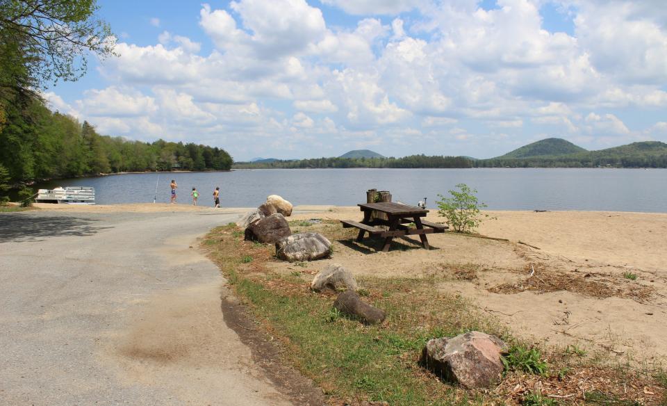 A beach with a boat ramp, picnic table, and mountain views